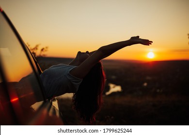 Woman enjoying beautiful view on the summer sunset, sitting with raised hands in car during a sunset. Woman and vehicle on beautiful sunset background. - Shutterstock ID 1799625244