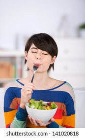 Woman Enjoying A Bowl Of Fresh Leafy Green Salad Salad Standing With Her Eyes Closed In Pleasure And A Fork In Her Mouth