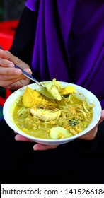 A Woman Is Enjoying A Bowl Of Traditional Laksa Dish That Consists Of Vermicelli, Tofu, Bean Sprouts, Egg, Herbs And Oncom From Bogor, West Java - Indonesia.