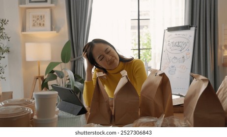 Woman enjoying a break at home, surrounded by delivery packages, relaxing with closed eyes at a cozy, sunlit dining table. - Powered by Shutterstock