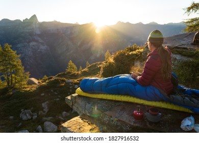 A woman enjoying breakfast from her bivouac on a beautiful morning in the mountains.
