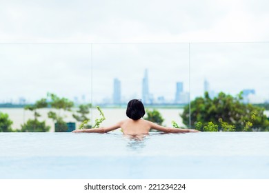 Woman Enjoying The City View From Infinity Pool