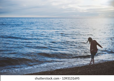 A Woman Enjoying The Evening Dipping Her Toe In The Water At The Oceans Edge