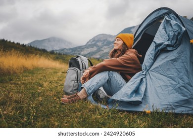 woman enjoying landscape sitting in the tent  alone  engoy nature and relax. Traveling and camping concept. Camping tent