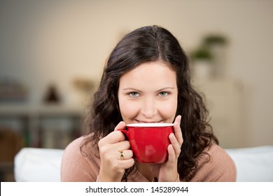 Woman enjoying a large cup of freshly brewed hot tea as she relaxes on a sofa in the living room