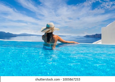 Woman enjoying relaxation in pool and looking at the view in Santorini Greece