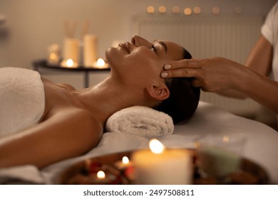 Woman enjoying relaxing anti-stress head massage and pampering in warm candle lighting ambient salon spa in luxury resort or hotel - Powered by Shutterstock