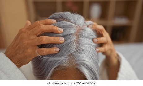 Woman enjoying relaxing head massage in serene spa setting with soft natural light highlighting her mature, silver hair and calm, soothing atmosphere of the wellness center - Powered by Shutterstock