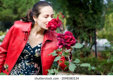 Woman Enjoying A Rose Bush With Red Leather Jacket