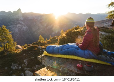 A woman enjoying the sunrise from her bivouac on a beautiful morning in the mountains. - Powered by Shutterstock