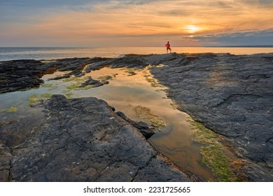 woman enjoying sunset at the rocky coast of Hookhead in southern Republic of Ireland near Annestown