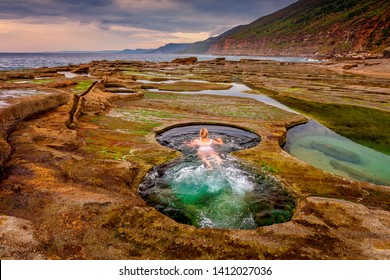 A Woman Enjoying A Swim In The Figure 8 Plunge Pools.  A Set Of Rock Pools Located On The Rock Shelf Exposed In Low Tide Only