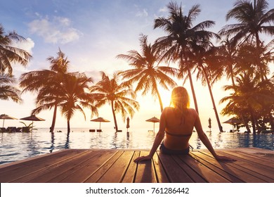 Frauen, die Ferien im luxuriösen Hotel am Strand mit Swimmingpool und tropischer Landschaft nahe dem Strand genießen