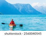 A woman enjoys kayaking in the clear blue waters of Norway