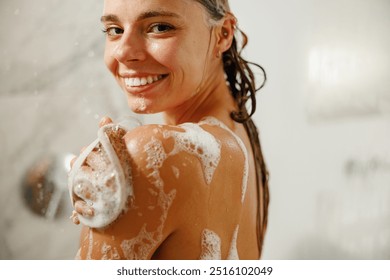 A woman enjoys a refreshing shower, joyfully using a foamfilled scrub brush to cleanse herself thoroughly - Powered by Shutterstock