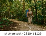 A woman enjoys trekking in a beautiful lush forest with a backpack and trekking poles