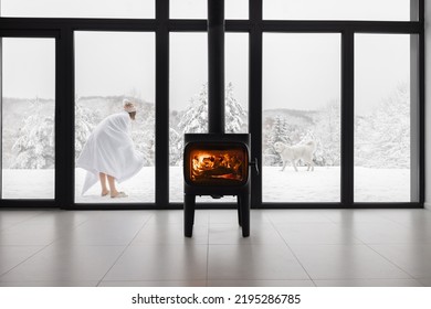 Woman Enjoys Winter Time Playing With Dogs Near House With Cozy Burning Fireplace. Concept Of Winter Vacation And Recreation In The Snowy Mountains