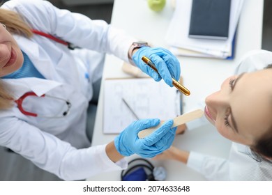 Woman ENT doctor conducts a medical examination of the throat of female patient top view. Methods for examining the oral cavity of the tonsils and pharynx concept