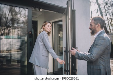 Woman Entering Office And Man Opening Door