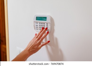 Woman Entering Security Pin Password On Home Security Alarm Keypad