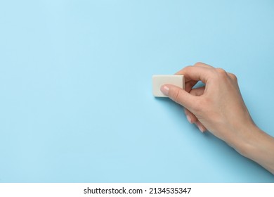 Mujer borrando algo sobre fondo azul claro, encerrando. Espacio para texto