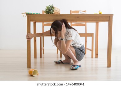 A Woman Evacuating Under A Table In An Earthquake