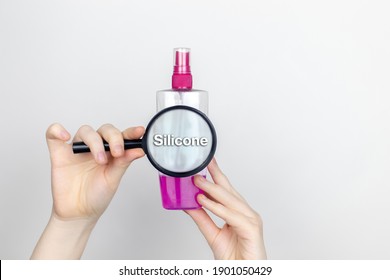 A Woman Examines The Harmful Ingredients Of The Hair Spray A Magnifying Glass. Means With Silicone. The Concept Of Hazardous Substances In Cosmetics And Household Chemicals