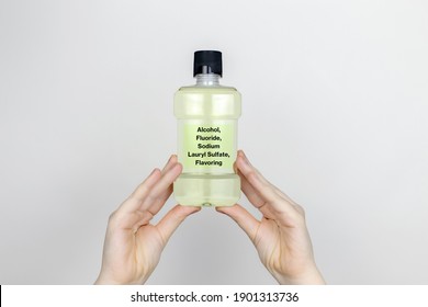 A Woman Examines The Harmful Ingredients Of The Mouthwash. Harmful Composition Of Ingredients. Rinse Aid With Alcohol, Fluoride, Sodium Lauryl Sulfate, Flavoring.