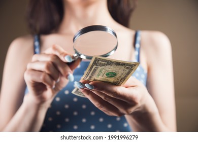 Woman Examines The Money With A Magnifying Glass. Counterfeit Check Concept