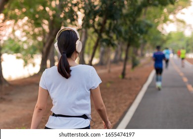 Woman Exercise Walking In The Park Listening To Music With Headphone