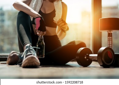 Woman exercise workout in gym fitness breaking relax after training sport with dumbbell and holdingmineral salt bottles healthy lifestyle bodybuilding, Athlete builder muscles lifestyle.