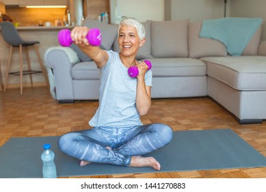 Woman Exercising With Dumbbell At Home. Feeling great inside and out! Age is no excuse to slack on your health. Portrait of smiling senior woman holding dumbbell - Powered by Shutterstock