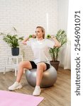 Woman exercising with dumbbells on a stability ball in a indoor space