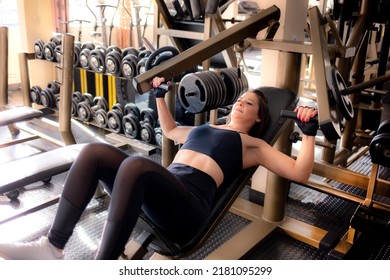 Woman exercising at the gym, lifting weights. Woman training on incline bench press machine. - Shutterstock ID 2181095299