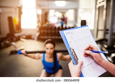 Woman exercising in gym, personal trainer, plan on clipboard - Powered by Shutterstock