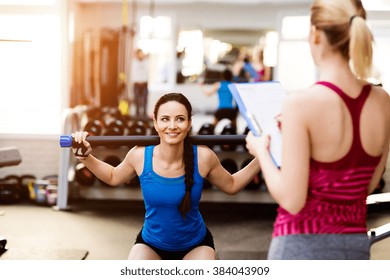 Woman Exercising In Gym, Personal Trainer, Plan On Clipboard
