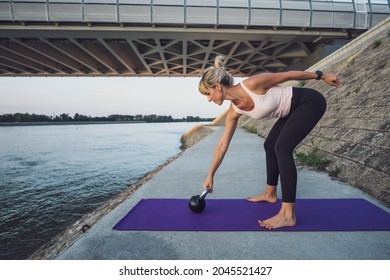 Woman Exercising Kettlebell Pilates Outdoor. Plank With Leg Lift Exercise.