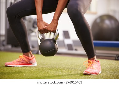 Woman exercising with a kettlebell weight, low-section crop
