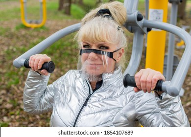 Woman Exercising On A High Pull Chair And Wearing Protective Face Mask, Open Gym