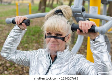 Woman Exercising On A High Pull Chair And Wearing Protective Face Mask, Open Gym