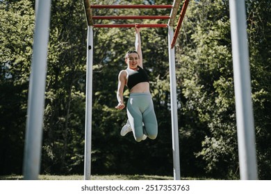 Woman exercising on monkey bars in a green urban park, focusing on strength and fitness through calisthenics on a sunny day. - Powered by Shutterstock