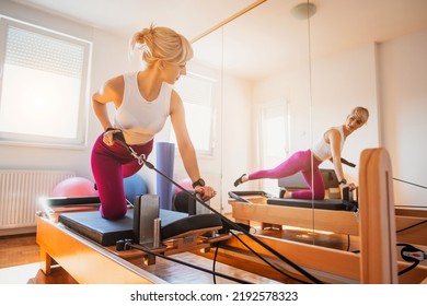 Woman is exercising on pilates reformer bed in her home. - Powered by Shutterstock