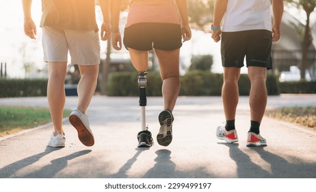 Woman exercising in a park with a friend providing support while using a prosthetic leg. People jogging side by side outside in a park. Female walking and exercise works out outside.  - Powered by Shutterstock