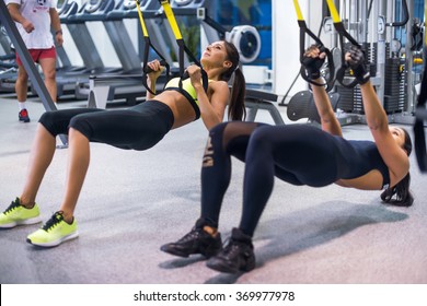 Woman exercising with suspension straps in fitness club or gym