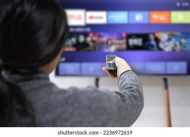 A woman experiences OTT service using a smart TV at home - Shutterstock ID 2236972619