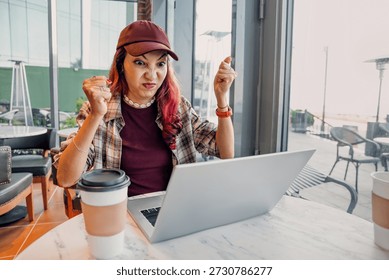 Woman experiencing tech problems, expressing frustration, and showing anger while using a laptop in a cafe