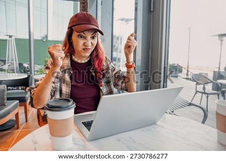 Woman experiencing tech problems, expressing frustration, and showing anger while using a laptop in a cafe