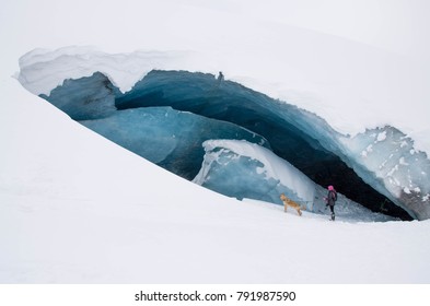 Woman Exploring Athabasca Glacier Cave In Banff / Jasper National Park Canada With  Adventurous Dog Pet