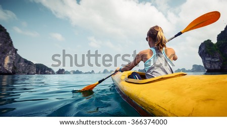 Woman exploring calm tropical bay with limestone mountains by kayak. Ha Long Bay, Vietnam