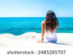 A woman exploring the Scala dei Turchi in Sicily, Italy, a stunning white limestone cliff formation overlooking the Mediterranean Sea, enjoying the natural beauty and scenic views of the coastal lands